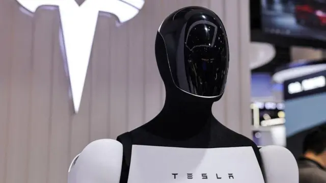 Un robot Tesla Optimus junto a un logotipo en el stand de la compañía en China.