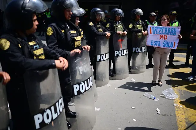 Una manifestante sostiene un cartel en el que dice 'Vizcarra no está solo' frente a una línea de policías
